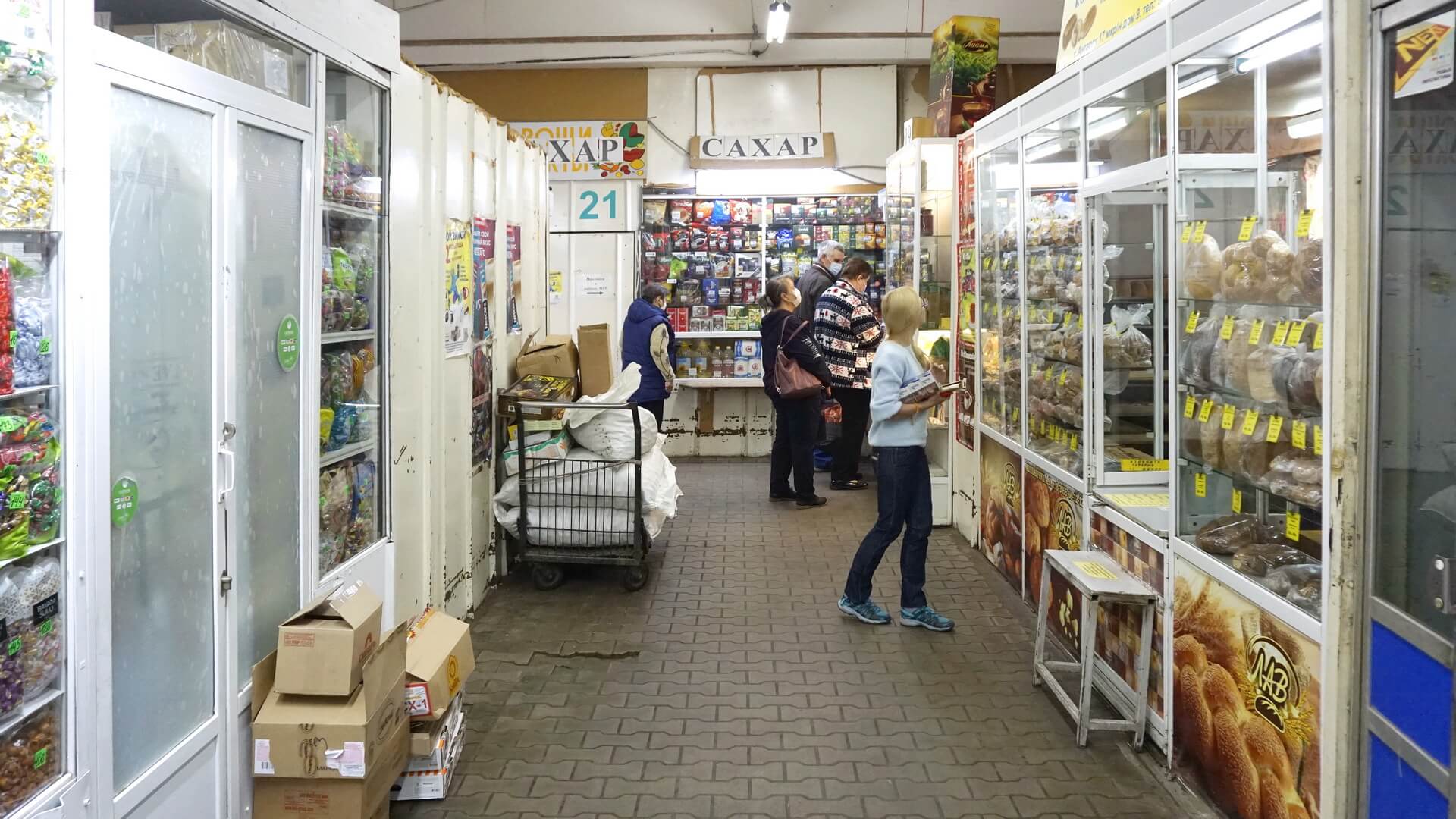 Покупатели выбирают сахар, консервы, чай в торговых павильонах бакалейных рядов продуктового рынка «Торгсервис»